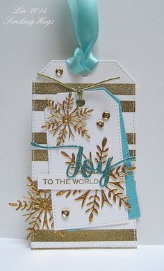 a white and blue tag with gold snowflakes on it that says joy to the world