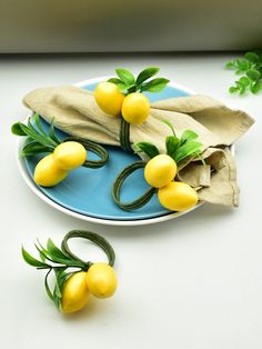 a plate topped with lemons on top of a white table next to green leaves