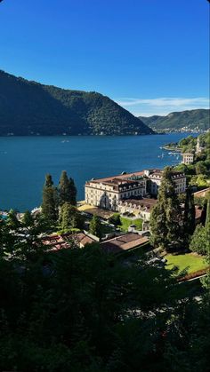 a large body of water surrounded by lush green trees and mountains in the distance with buildings on both sides