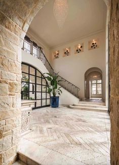 a large foyer with stone steps and an arched doorway leading to the second floor that has a potted plant in it