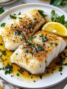 two fish on a plate with lemon and parsley