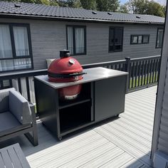 a bbq grill sitting on top of a wooden deck next to a gray couch