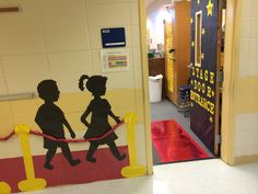 two children are walking down the red carpet in front of an entrance to a school