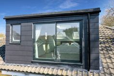 an image of a house that is made out of black shingles and has large windows