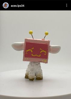 a small toy with yellow eyes on it's head and legs, standing on a white surface