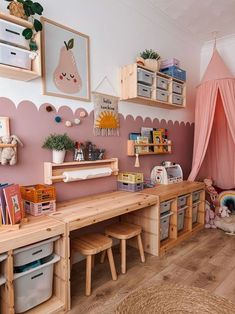 a child's bedroom with pink walls and wooden furniture, including a bed canopy