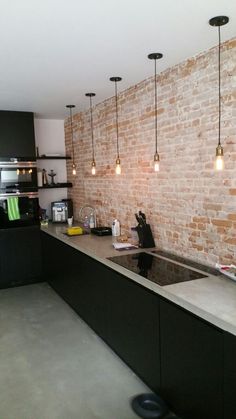 a brick wall in a kitchen with lights hanging from the ceiling and an island counter