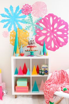 a birthday party with colorful paper decorations and cake on a shelf in front of the wall