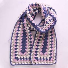 a crocheted scarf on a white surface with pink and blue squares in the middle