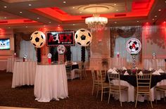 a room with tables and chairs decorated for a soccer themed event, including two giant balls in the center