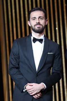 a man in a tuxedo is posing for the camera with his hands on his hips