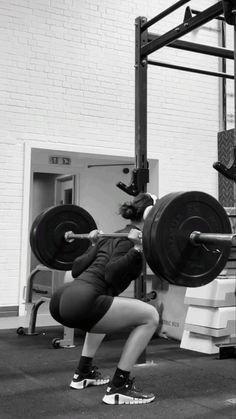 a woman is squatting while holding a barbell