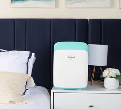 a white and pink air purifier sitting on top of a bed