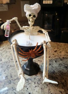 a skeleton sitting on top of a black bowl