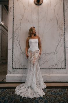 a woman standing in front of a marble wall