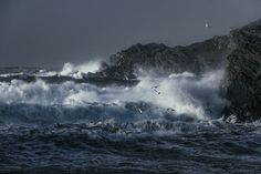 some birds are flying over the waves in the ocean and on top of an island