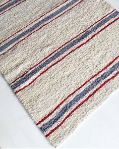 a white rug with red, blue and grey stripes on it sitting on a table