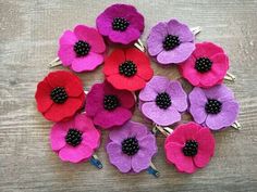 felt flowers with black centers are arranged on a wooden surface