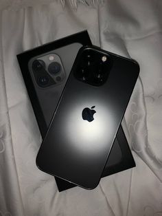 two black iphones sitting on top of a white bed next to eachother