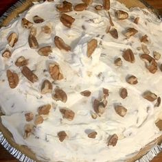 a pie with white frosting and nuts on top