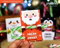 a hand holding up a candy cane in front of some christmas themed cards on a table