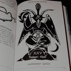 an open book with black and white illustrations on the pages, including devil's head