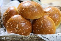 four buns in a basket with sesame seeds on top, ready to be eaten