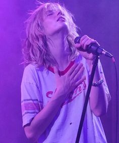 a woman singing into a microphone on stage