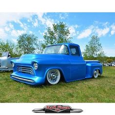 an old blue pickup truck parked in a field with other classic cars behind it and the words, ford on the front