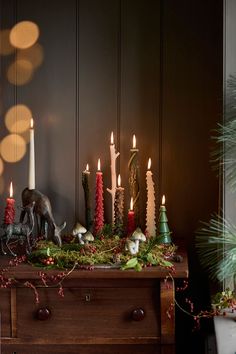 a table topped with lots of candles next to a christmas tree