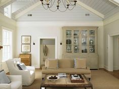 a living room filled with furniture and a chandelier hanging from the ceiling over a coffee table