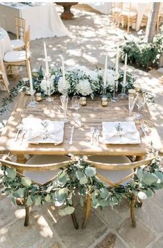 the table is set with white flowers and greenery