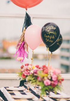 three balloons with writing on them sitting on a table next to flowers and other decorations