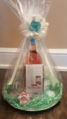 a wine bottle wrapped in plastic and sitting on top of a wooden table next to a card