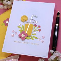 a handmade card with an orange drink and flowers