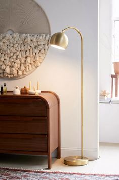 a living room with a lamp, dresser and rug on the floor in front of it