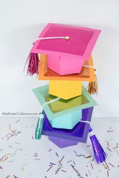 a stack of colorful graduation caps and tassels on top of confetti