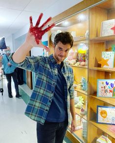 a man holding up his hand in front of a display case with cards and greetings on it