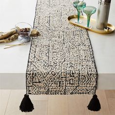 a table runner with tassels on it and other items sitting on the floor