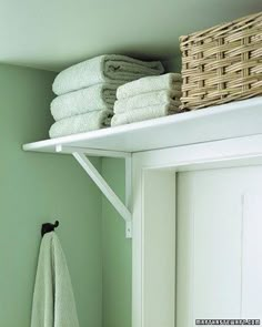 towels are stacked on top of the shelf above the door and in front of it is a towel rack