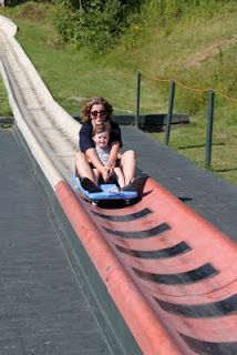 a woman and her child are sliding down a ramp