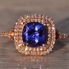 a tan gold ring with a blue stone surrounded by diamonds