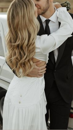 a bride and groom kissing in front of a car