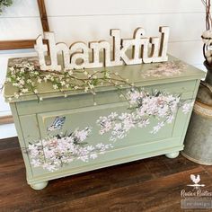 a painted chest with the word thank written on it and flowers in front of it