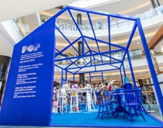 a large blue structure in the middle of a building with people standing around and eating