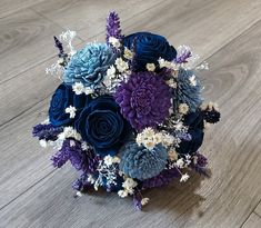 a bouquet of blue and purple flowers sitting on top of a wooden floor