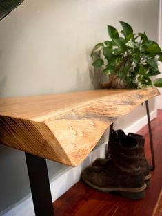 a wooden bench sitting on top of a hard wood floor next to a potted plant