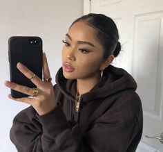 a woman taking a selfie in front of her cell phone wearing a hoodie