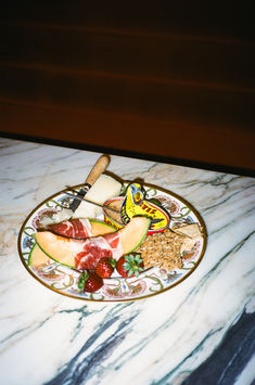 a plate full of assorted fruits on a marble counter top with a knife and fork