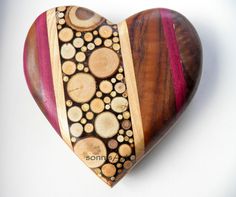 a heart shaped wooden object with wood slices and circles on the inside, sitting on a white surface